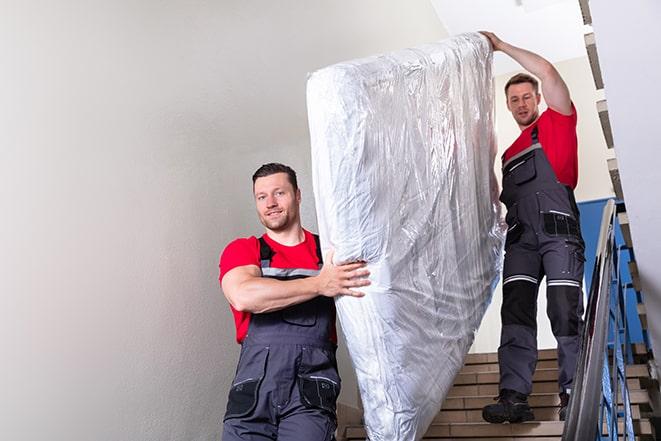 tackling the task of transporting a box spring out of a building in Maplewood