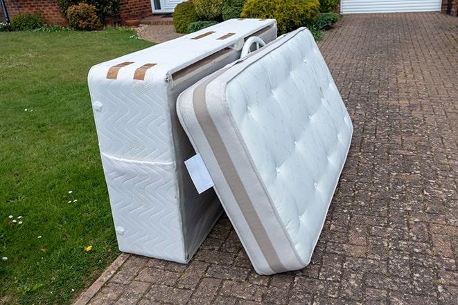 small truck hauling away a worn-out mattress